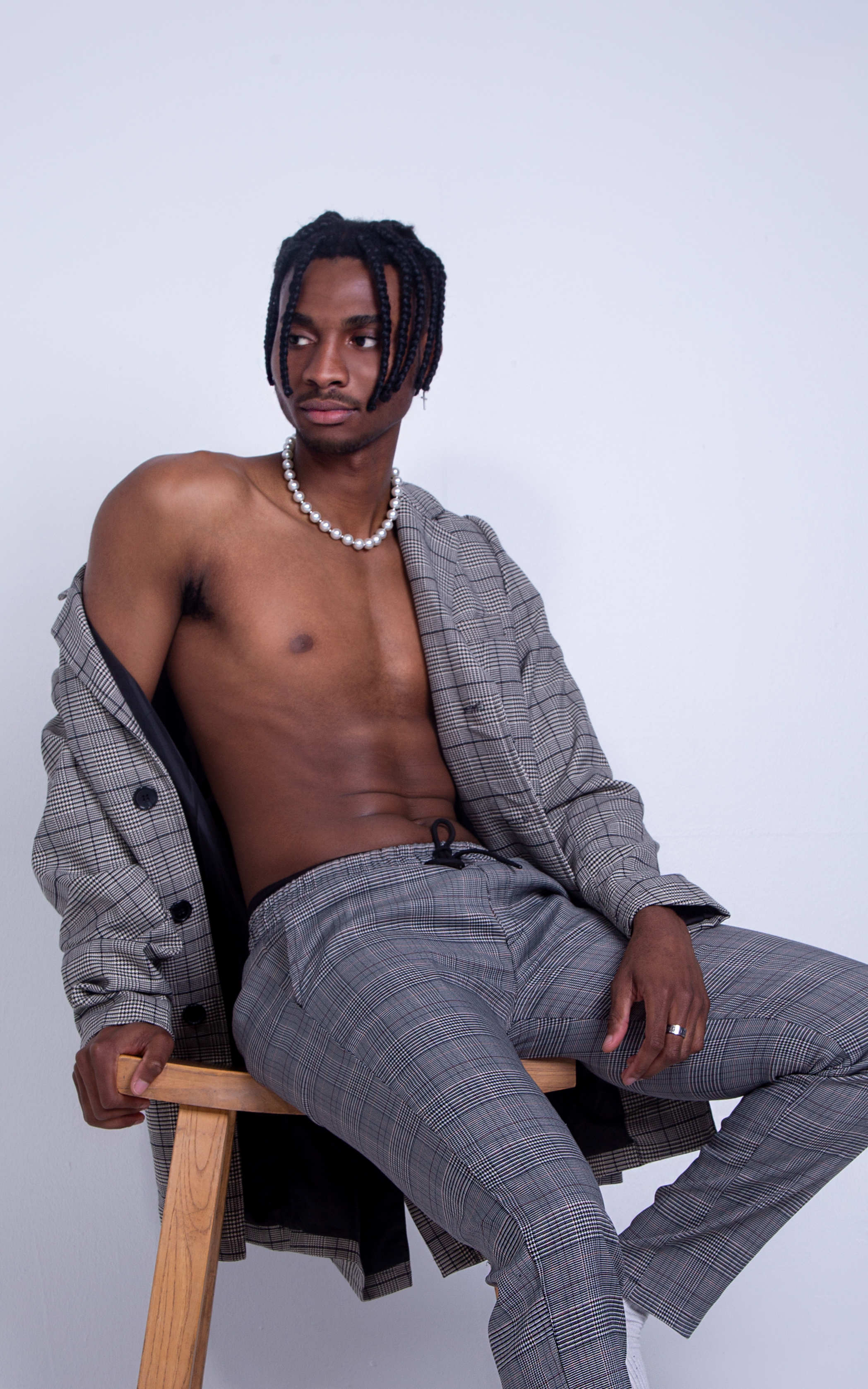 Full body photograph of man sitting on a chair shirtless with a suit